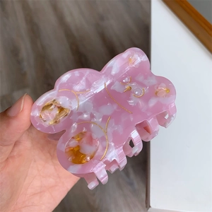 Close-up of pink marble pattern acetate hair claw clip with golden bear engraving
