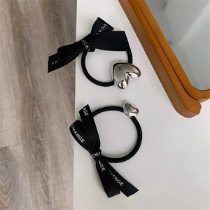 Detail of black hair tie with lucky lettering ribbon and silver heart pendant charm