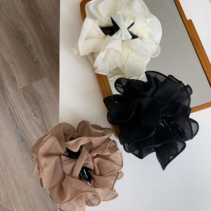 Detailed macro view of elegant layered organza flower hair claws in cream and black