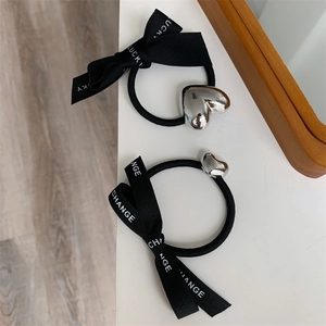 Close-up of black ribbon hair ties with silver heart charms and Lucky Change text