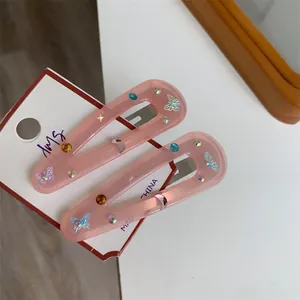 Close-up of pink translucent butterfly hair clips with colorful rhinestones on a white card