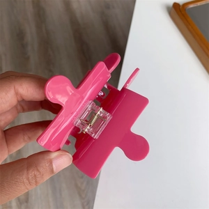 Detail view of pink jigsaw puzzle hair claw clip with visible metal spring mechanism