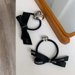 Detail of high-elasticity hair ties with silver heart charms and LUCKY ribbon bows