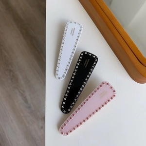 Gros plan de barrettes géométriques en acétate avec strass et lettrage doré élégant