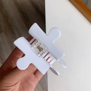 Close-up of white puzzle block acetate hair claw clip with transparent spring mechanism