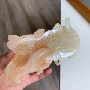 Detailed close-up of a double cat acetate hair claw with marble texture and gold accents