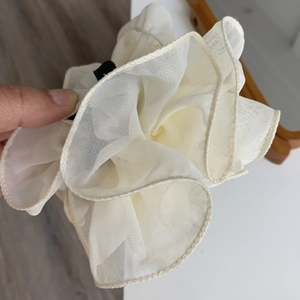 Detailed view of cream ruffled mesh flower hair claw clip with delicate layered organza edges