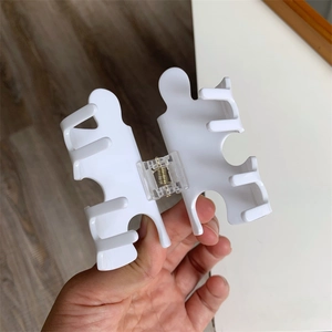 Macro shot of creative white puzzle piece hair claw clip with golden metal spring