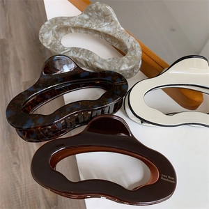 Close-up of four geometric acetate hair claws in marble and tortoiseshell patterns