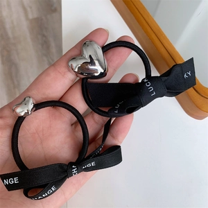 Elastic hair tie with silver heart pendant and ribbon bow featuring Lucky lettering