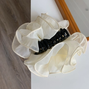 Detailed close-up of cream white ruffled mesh hair claw clip with a layered fabric texture