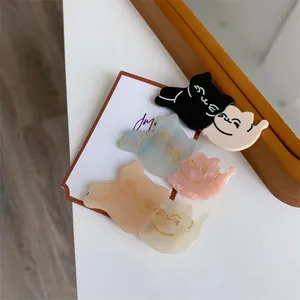 Close-up of cat-shaped acetate hair clips in six colors on a white display card