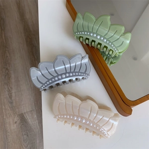 Close-up of elegant acetate hair claws with wave design and pearl inlay in three colors