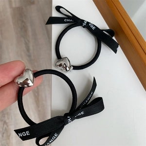 Elegant black elastic hair tie featuring a polished silver heart charm and ribbon bow accessory