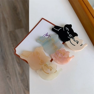Close-up of five colorful cat-shaped hair clips in black, blue, pink, and cream colors