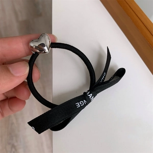 Detail of black elastic hair tie with silver heart charm and printed ribbon decoration