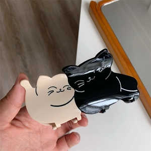 Detailed close-up of a cute dual-cat cartoon hair claw clip in black and white finish