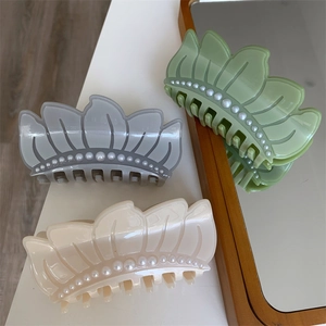 Close-up of three acetate shark hair clips with pearl details in morandi grey and cream