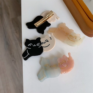 Detail showing colorful acetate cat hair clips with metal duckbill backings in four colors