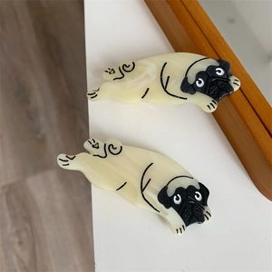 Detail von zwei Acetat-Mops-Haarspangen in Creme-Marmor-Optik auf einer weißen Oberfläche