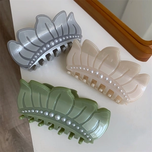Three lotus-shaped acetate hair claws with pearls in grey, beige, and green colors
