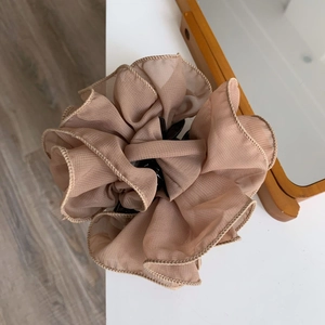 Close-up of elegant ruffled tulle flower hair claw clip in a soft champagne nude color
