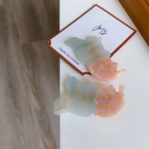Detail of four cute cat-shaped acetate hair clips in pastel blue and pink on display card
