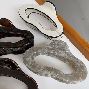 Close-up of four geometric acetate hair claws in marble and tortoiseshell patterns