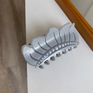 Detailed view of grey acetate hair claw with elegant white pearls and wavy flower petal design
