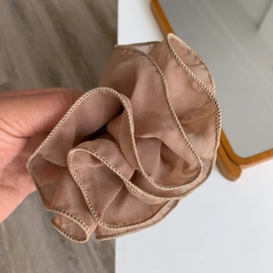 Detailed view of the champagne mesh hair scrunchie with soft ruffled edges and elastic band