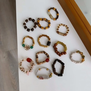 Vue à plat de 12 bagues perlées faites main avec pierres naturelles et perles de bois