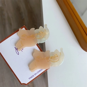 Detail of cute cat-shaped hair clips in orange and cream with gold etched faces