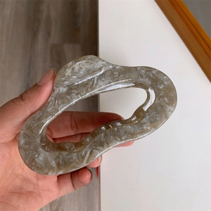 Detailed close-up of a large irregular marble pattern hair claw clip held by hand