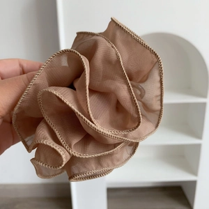 Detail of elegant champagne ruffled organza hair scrunchie with layered wavy edges
