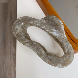Detail of marble pattern acetate claw clip with irregular hollow design and gold logo