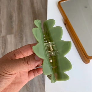 Detail of light green leaf-shaped hair claw clip with matte resin texture and spring