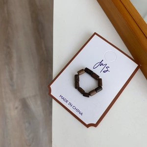 Gros plan d'une bague artisanale en perles de bois foncé avec grain de bois naturel