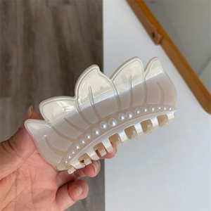 Detail of cream acetate hair claw clip featuring elegant rows of faux pearls on leaf shape