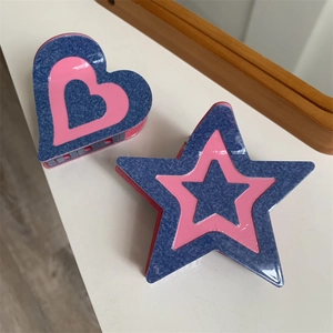 Détail de pinces à cheveux en acétate en forme de cœur et d'étoile, design rouge et bleu