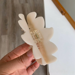 Detail of cream acetate lotus pearl hair claw clip with golden metal spring mechanism