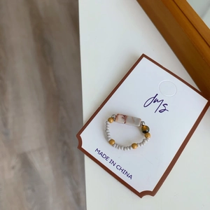 Gros plan d'une bague faite main en perles avec pierre naturelle sur carte de marque