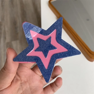 Pince à cheveux étoile avec couches de texture denim rose et bleue en gros plan de main