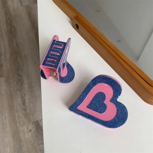 Détail de la pince à cheveux cœur rose et bleu avec texture denim sur miroir en bois