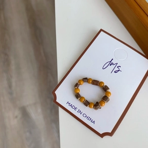 Détail d'une bague artisanale avec perles en bois marron et perles jaunes