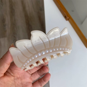 Detail of cream acetate hair claw clip featuring elegant pearl embellishments and a leaf design