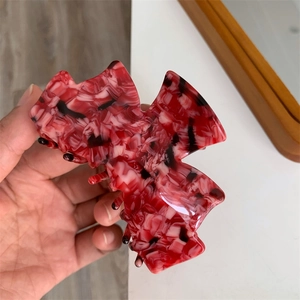 Détail de la pince à cheveux en acétate marbré rouge et blanc avec finition polie
