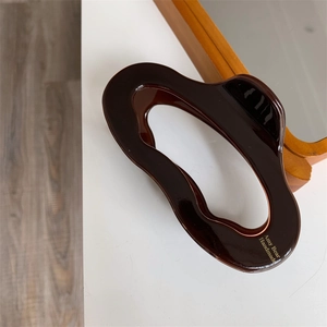 Detail of tortoise shell acetate hair claw clip with golden brand logo on a desk