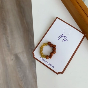 Détail d'une bague élastique faite main avec des perles en bois et pierres jaunes