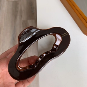 Close-up of deep brown tortoiseshell acetate hair claw clip with a wavy oval design