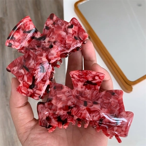 Détail de la pince à cheveux en acétate motif fraise rouge et texture marbrée